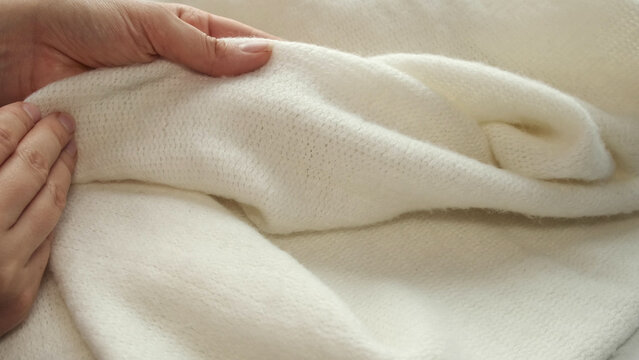 Female's Hand On The Fabric Of White Plush Cloth With Soft Nap. Clothing Industry Concept, Slow Motion. Woman Checking The Quality Of Clothes, Enjoys The Soft Pleasant Texture Of The Fabric