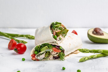 burrito. fresh tortilla wraps with vegetables asparagus, avocado, tomatoes, peas, cheese and tartar sauce