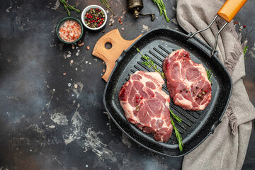 Raw fresh meat steaks on frying pan on a dark background. banner, menu, recipe place for text, top view