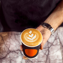 Latte coffee art close up, man holding coffee cup, making latte art