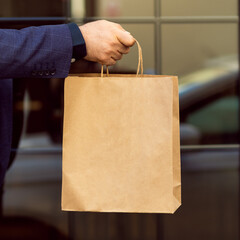 Man hand holding a paper bag outside. Using a paper bag to save environment concept
