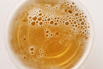 Light beer in a glass with foam and bubbles close-up, top view, isolated on white