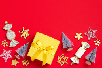 Christmas border with golden gift box with mini Christmas trees and baubles on bright red background