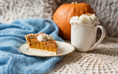 Pumpkin pie topped with whipped cream with coffee or chocolate and pumpkin in backround, rustic set with blue accents