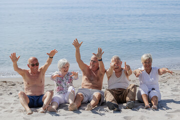 Un gruppo di anziani si diverte seduti nella spiaggia in riva al mare  