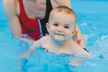 A swimming teacher teaches a little boy to swim in the pool. Children's first swimming lessons....