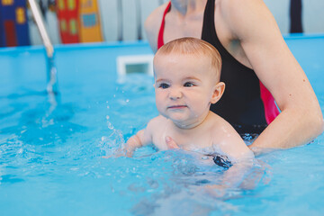 A swimming teacher teaches a little boy to swim in the pool. Children's first swimming lessons....