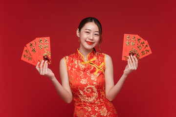 Young asian woman wearing qipao cheongsam dress with red envelopes on red background for Chinese...