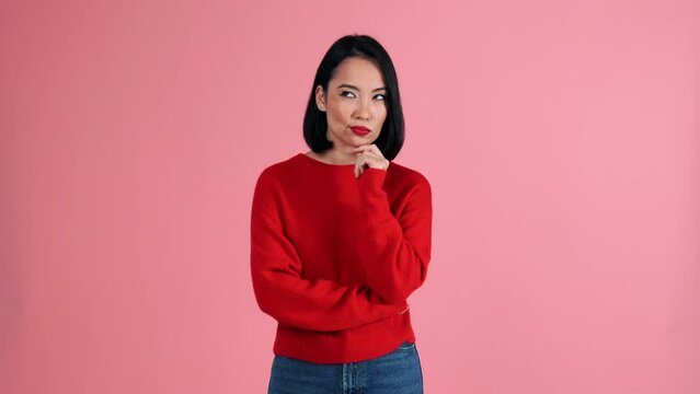 Pensive Asian woman wearing red sweater showing no gesture at the camera in the pink studio