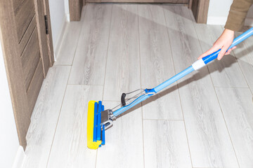 Cleaning the house. A woman washes a laminate floor in the hallway with a mop