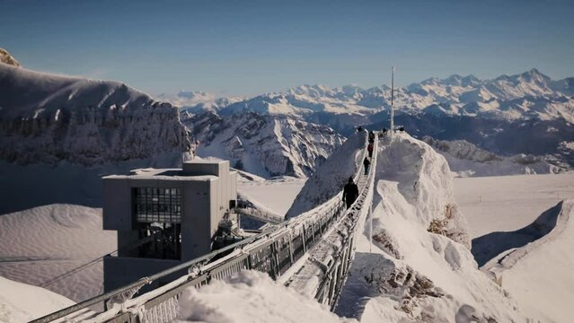 The man walking through the Peak Walk bridge on Sex Rouge in a beautiful sunny winter day. Glacier 3000 in December 2021