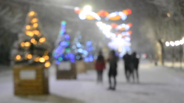 People walking street decorated many Christmas trees during heavy snowfall on winter night. New Year Christmas celebrate holidays. Decor decorations street garlands street lighting. Blurred background