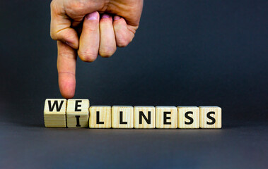 Wellness or illness symbol. Concept words Wellness and Illness on wooden cubes. Doctor hand. Beautiful grey table grey background. Medicak, healthy lifestyle wellness or illness concept. Copy space.