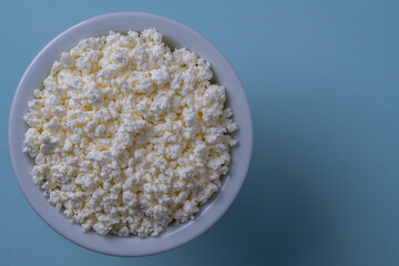 White cottage cheese in plate on blue background, top view, close up, copy space