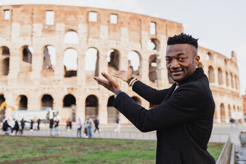 an African boy presents showing the coliseum with his hands.