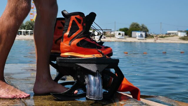 Shoes for flyboarding on the seashore. A man puts on his shoes before flying. Slow motion.