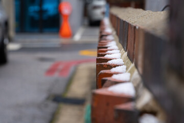 Selective focus of snow on a jagged red brick wall