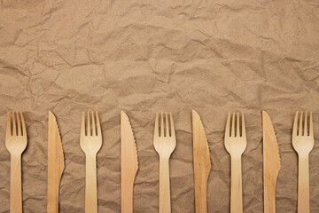 Set of wooden forks and knifes on crumpled paper background