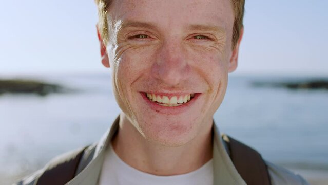 Beach, smile and face of man happy on global travel journey for adventure, freedom and happiness on student gap year. Peace, ocean sea water and nature portrait of calm gen z person in Dublin Ireland