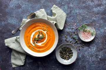 Pumpkin and carrot soup served with cream and seeds. Top view with copy space. Healthy food.