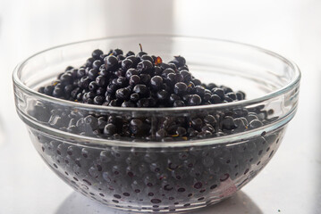 blueberries in a large glass bowl on a white table background