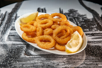 Roman squid with a piece of lemon served on a plate