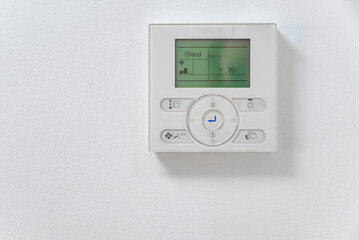 Close-up electronic thermostat on a white wall