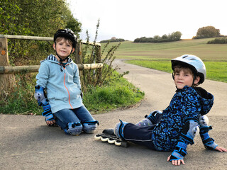 Two little kids boys skating with rollers in the city. Happy children, siblings and best friends in...