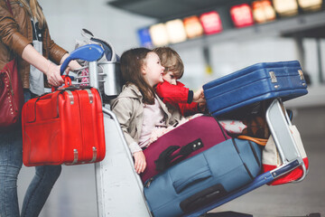 Two little kids, boy and girl, siblings and mother at the airport. Children, family traveling,...