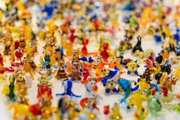 Fototapeta na wymiar Multi-colored miniature glass toys in large quantities on a uniform surface. Soft selective focus, festive positive background image for joyful events. Copy space