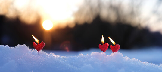 red candles heart on snow, abstract blurred natural background. beautiful winter landscape with...