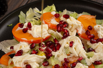 Salad with persimmon, strachatella cream cheese and pomegranate, open space