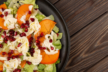 Salad with persimmon, strachatella cream cheese and pomegranate, open space