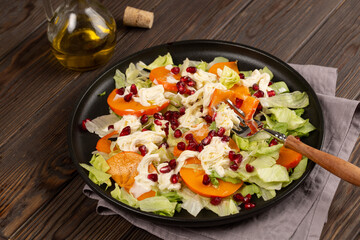 Salad with persimmon, strachatella cream cheese and pomegranate, open space