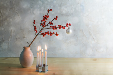 Minimalist fourth advent with four small burning candles and a berry branch with a white christmas...