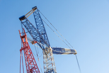 Metal crane and cables against the blue sky.