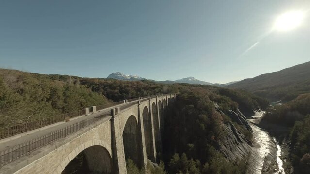 Fly over a road over an old stone bridge in the mountains