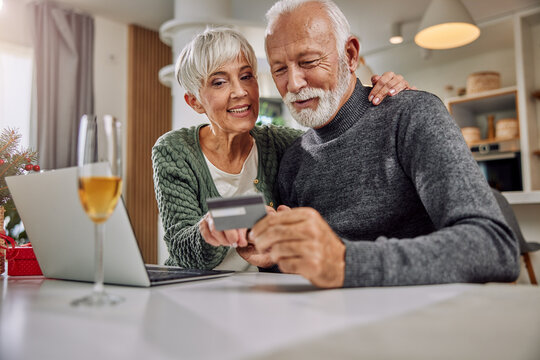 an embracing elderly couple shopping online for Christmas - Powered by Adobe