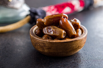Dried dates fruit in bowl on black table.