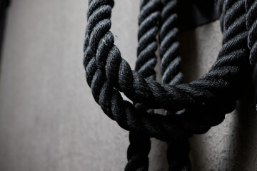 Close up of black battle rope on a gray backgound. Sport and fitness equipment. Functional training.