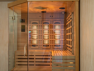 Wooden Finnish sauna in apartment. Glass door.
