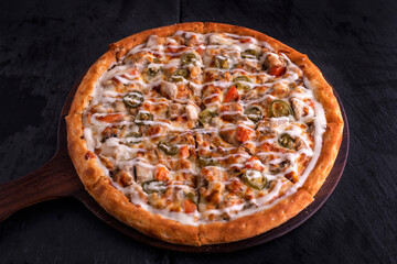 BBQ Chicken Ranch pizza isolated on cutting board top view on dark background italian fast food