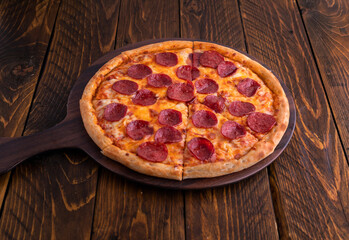Pepperoni pizza isolated on cutting board top view on dark background italian fast food