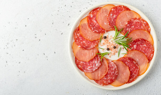 Thin Slices Of Salami Sausage And Turkey Raw Dried Sausage. Overhead Shot In A Round Plate On Light Background