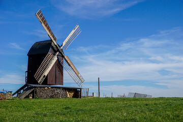 Fototapeta premium Windmühle an einer Wiese mit blauem Himmel