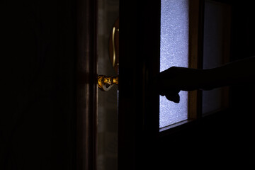 Woman's hand opens the door in the dark at home