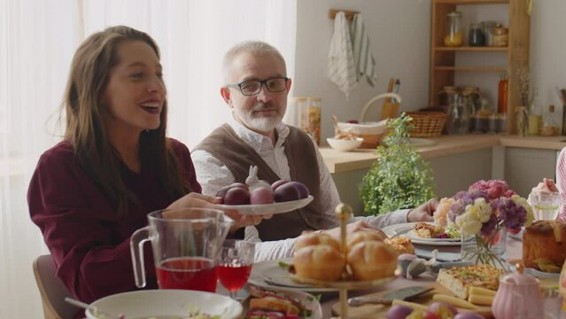 Grandmother passing plate of dyed eggs to daughter having Easter dinner with family at home