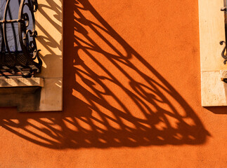 THE SHADOW OF A BALCONY GRATING PROJECTED ONTO AN ORANGE WALL