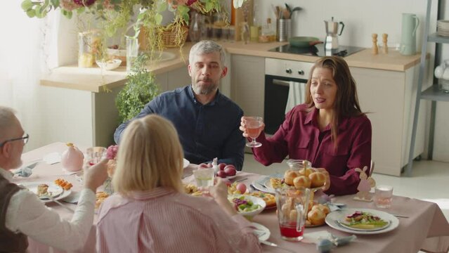 High angle shot of family clinking glasses in toast and drinking while having festive Easter dinner at home