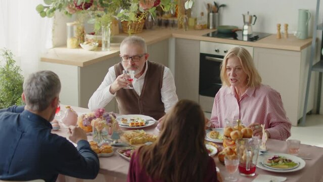 High angle shot of family eating festive dinner and speaking while celebrating Easter together at home